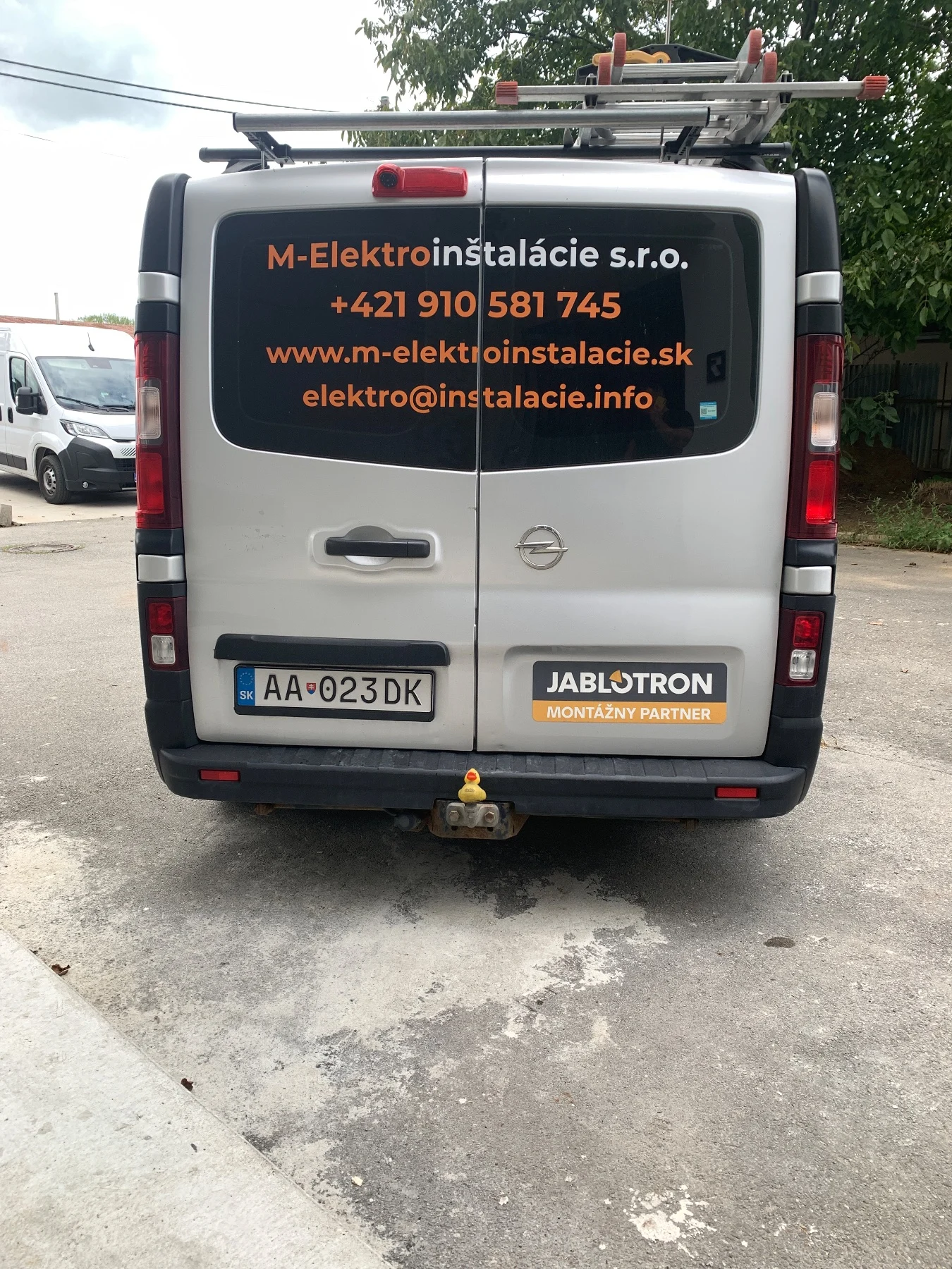 Zadná časť firemnej dodávky s polepom M-Elektroinštalácie a kontaktnými údajmi – fotografia 1